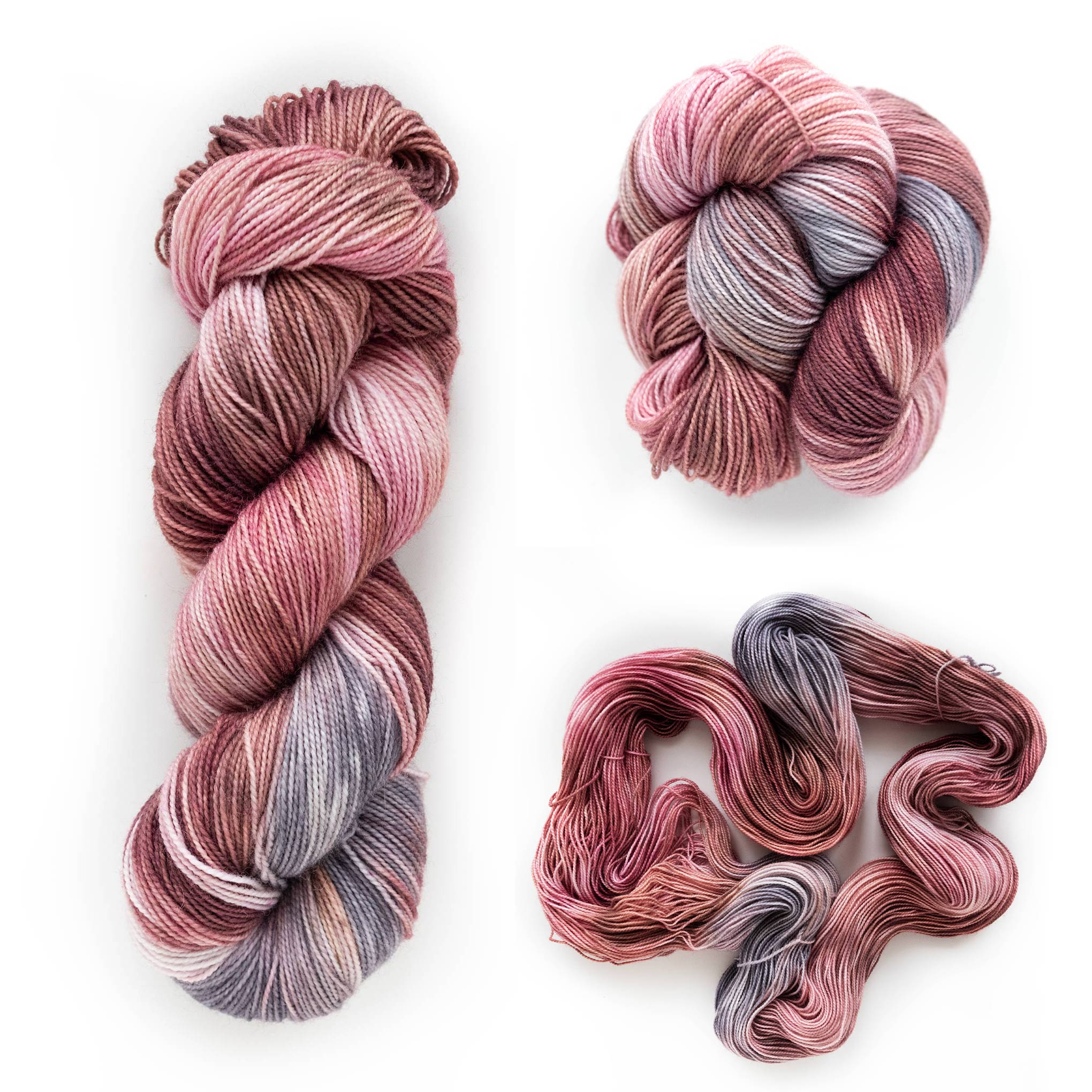 Hand dyed yarn in the Rosewood Mist colorway showing soft muted rose, mauve, and grey tones.